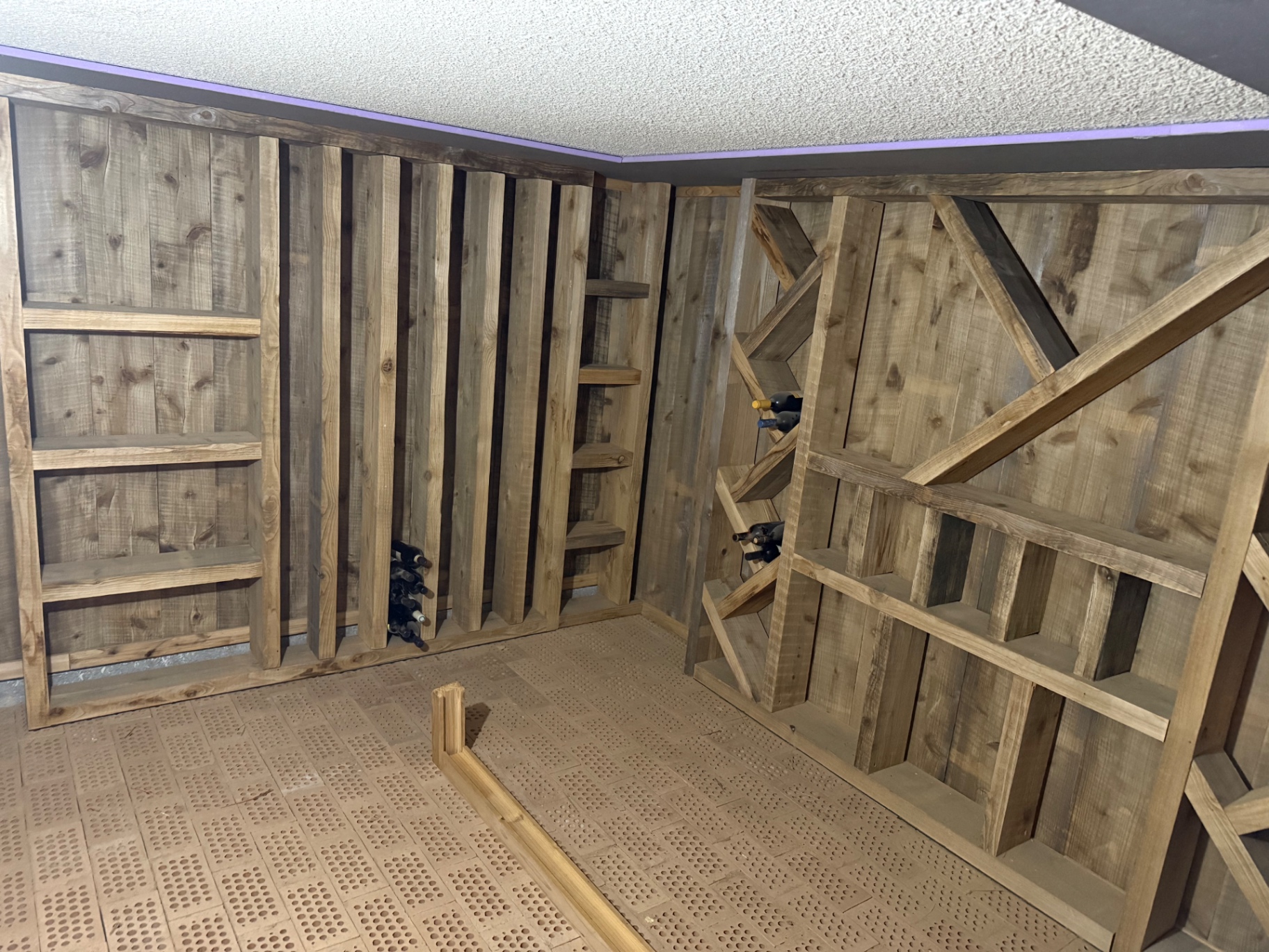 Vue d'ensemble d'une cave aménagée en bois avec casiers, niches et rangements pour bouteilles