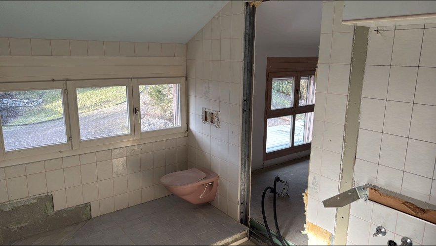 Salle de bain vidée avec cloison ouverte vers la pièce voisine