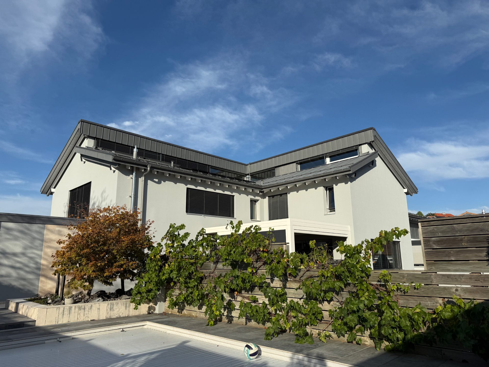 Façade de villa suisse peinte en blanc avec avant-toits gris anthracite