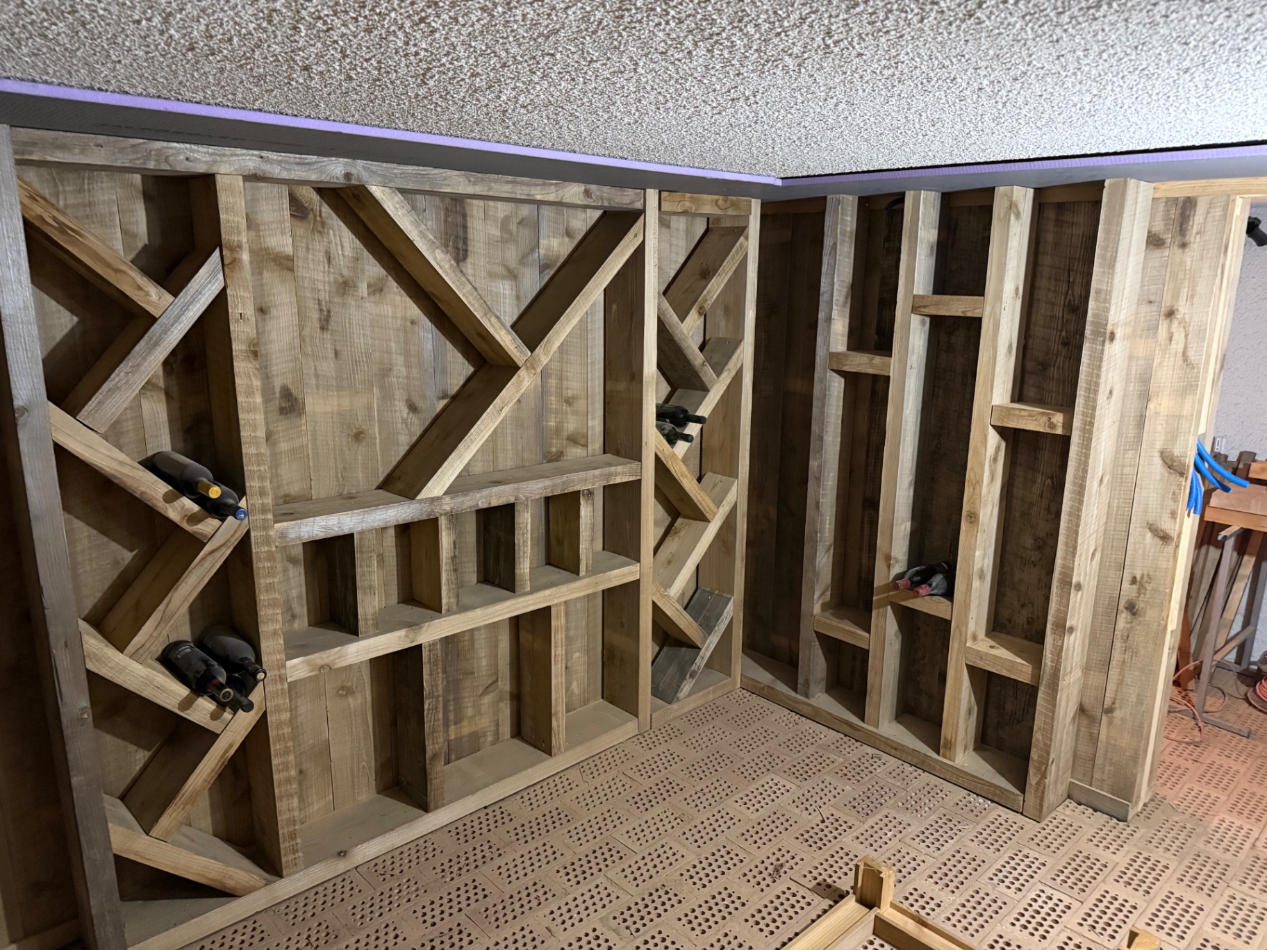 Rangements en bois garnis de bouteilles dans la cave terminée