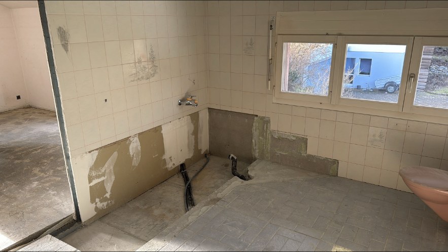 Salle de bain en cours de démontage : sanitaires retirés, murs carrelés et sols préparés