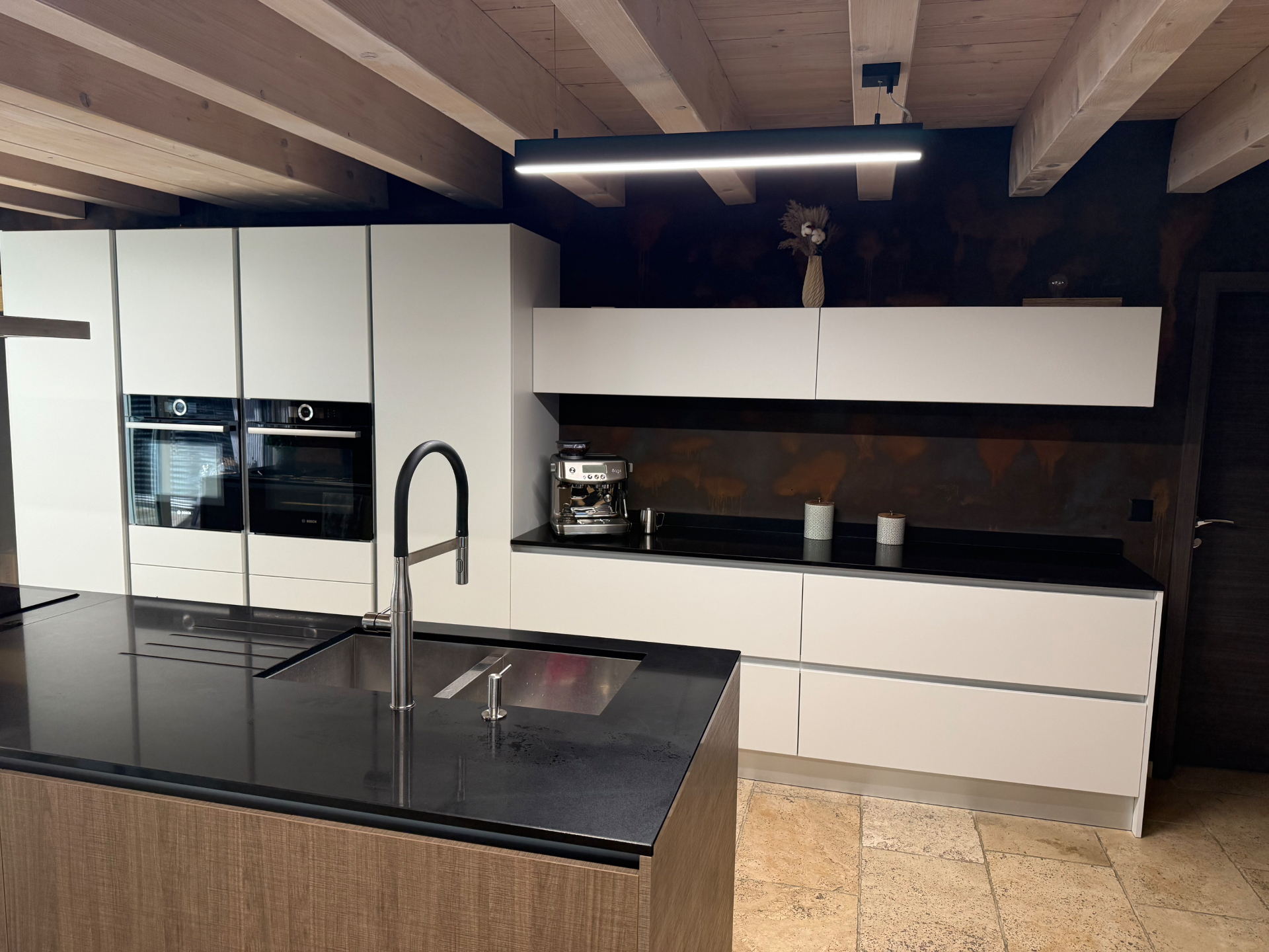 Mur de cuisine traité en peinture décorative effet métal oxydé derrière un plan de travail noir