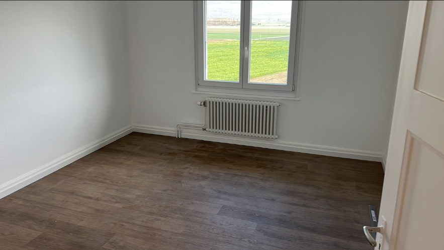 Chambre aux murs blancs avec radiateur repeint sous la fenêtre