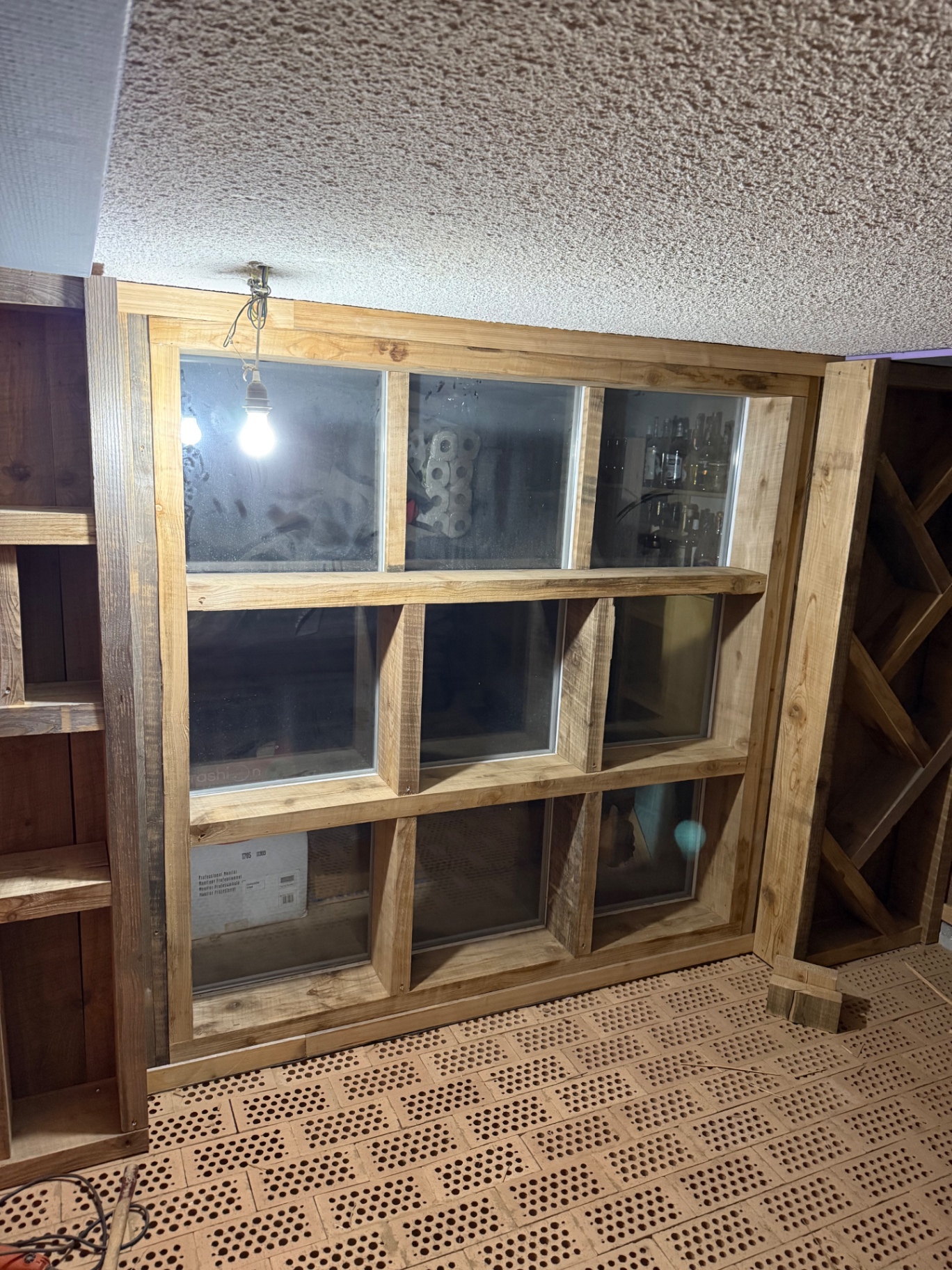 Rangements en bois réalisés devant une verrière intérieure dans une cave
