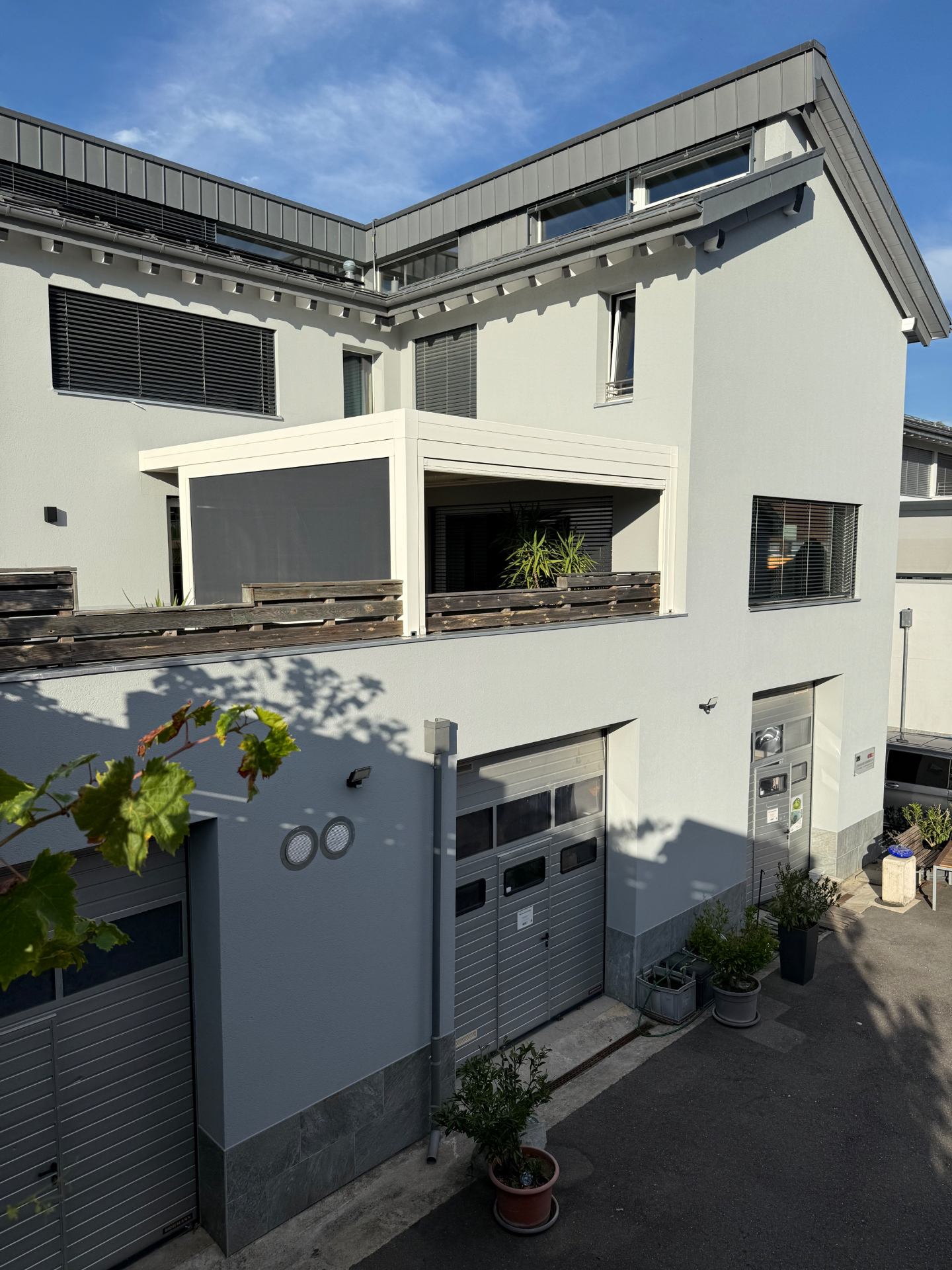 Façade extérieure peinte avec soubassement gris, garages et avant-toit traité