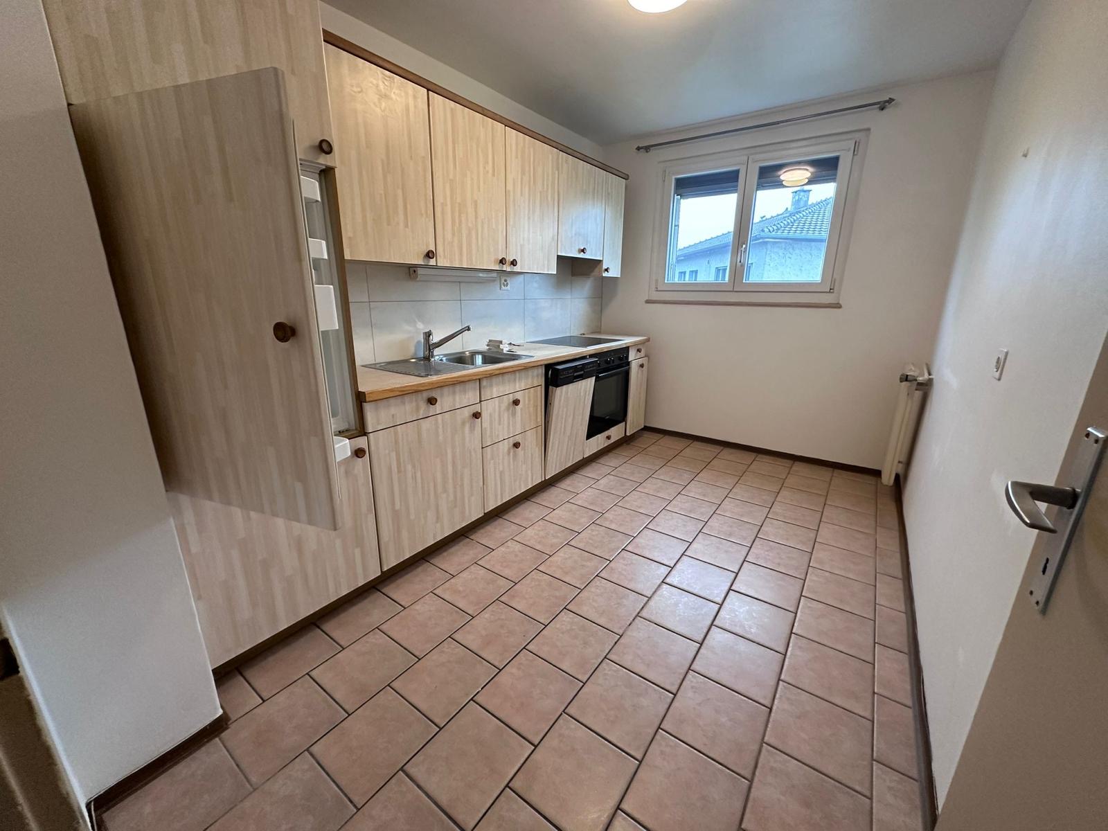 Cuisine avant travaux : façades en bois clair, carrelage rose et murs beiges